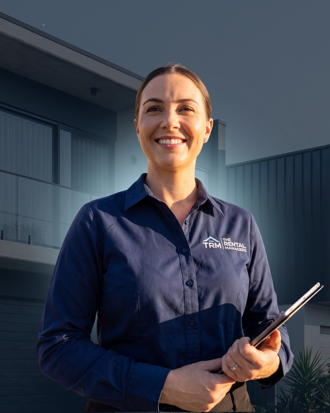 A smiling Rental Managers property manager holding a tablet in front of a modern North Queensland home.